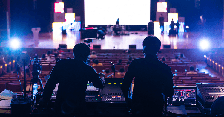 Two operators at front of house, working surrounded by show control equipment