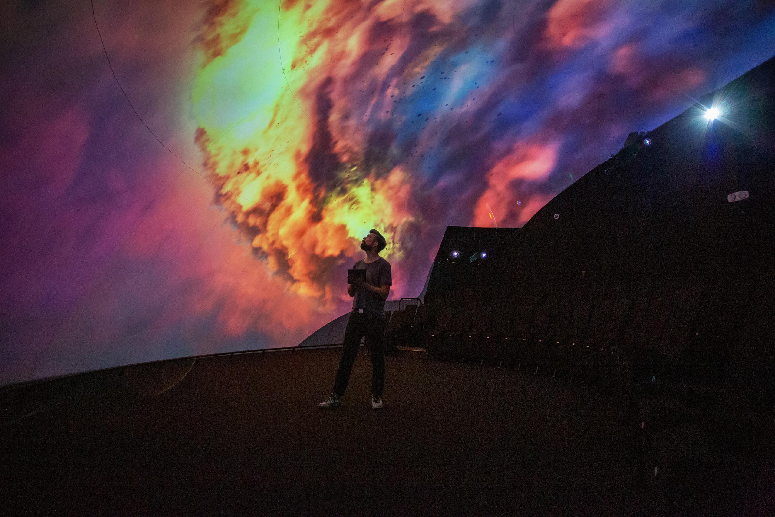 A person standing in front of a curved screen with immersive projection powered by Screenberry media server