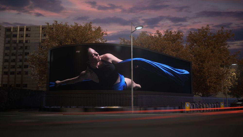 A woman displayed on a large curved street screen, showcasing Screenberry's role in driving visuals for 'Living Canvas' media installations