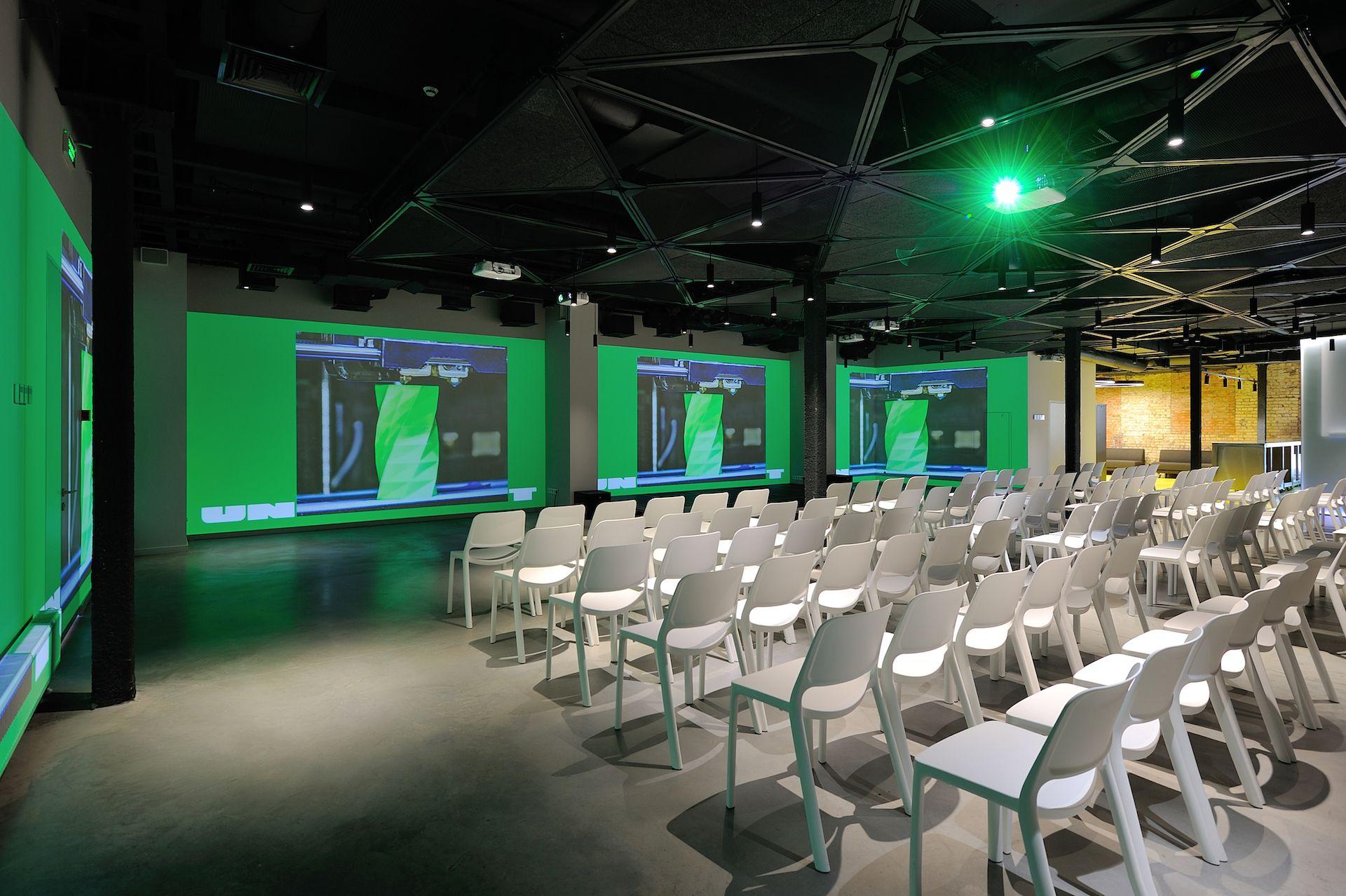 An auditorium with multiple projection screens, showcasing Screenberry's multi-screen playback at UNIT.Core