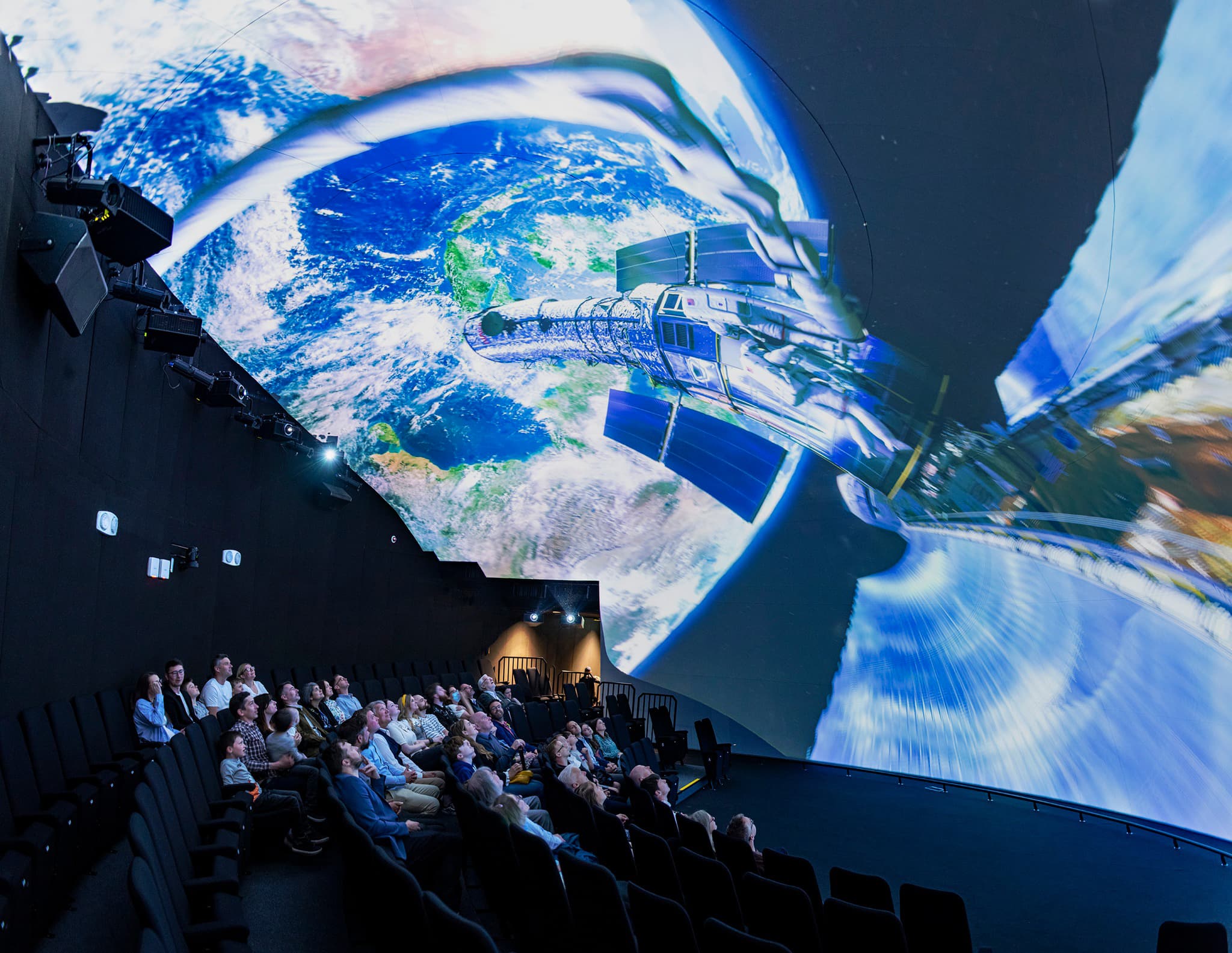 Group of people watching a Screenberry-powered projection at the Space Dome of Jodrell Bank's First Light Pavilion.