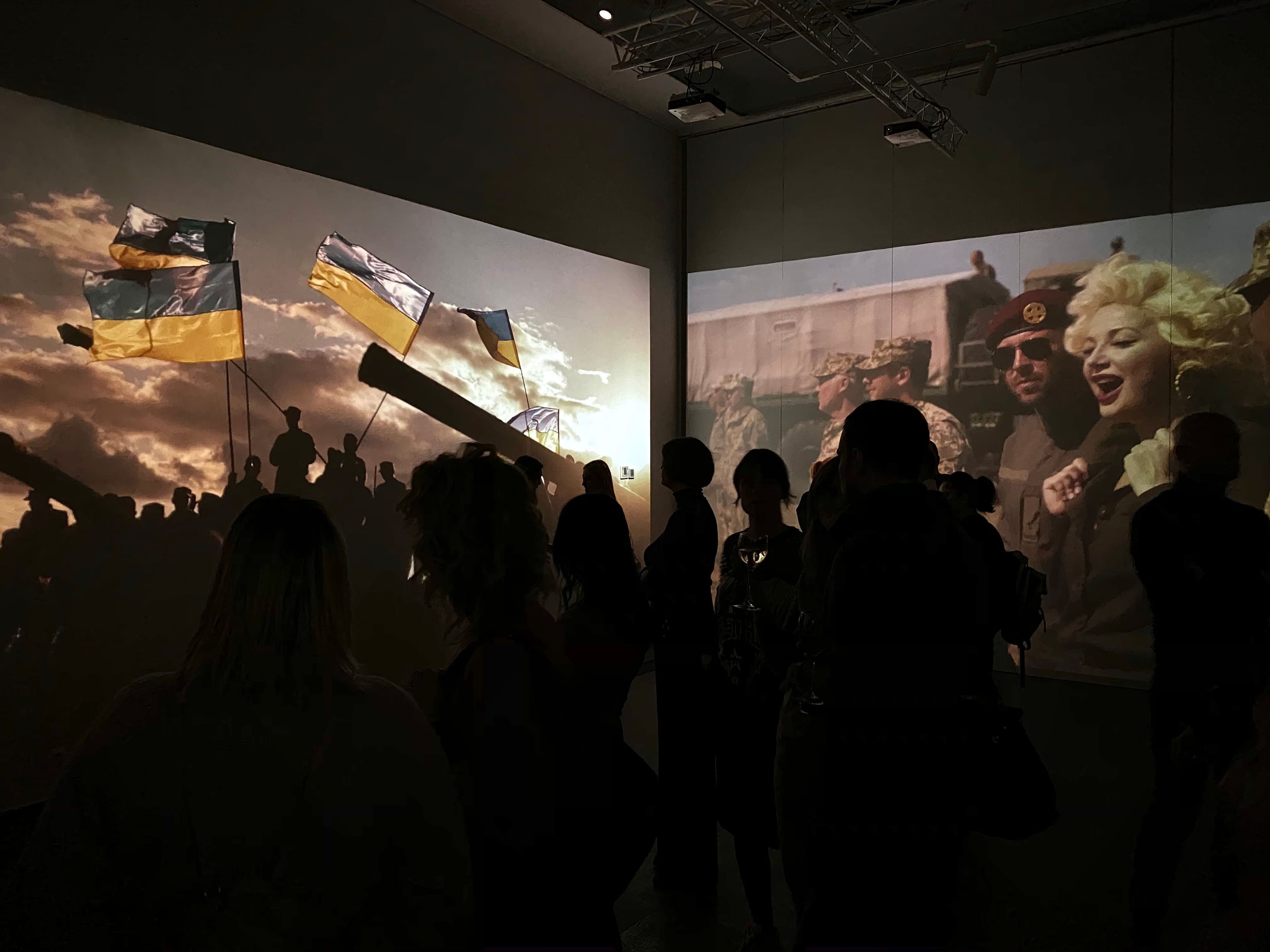 A group of people captivated by large projector screens driven by Screenberry at the “Voices of Love” digital art exhibition